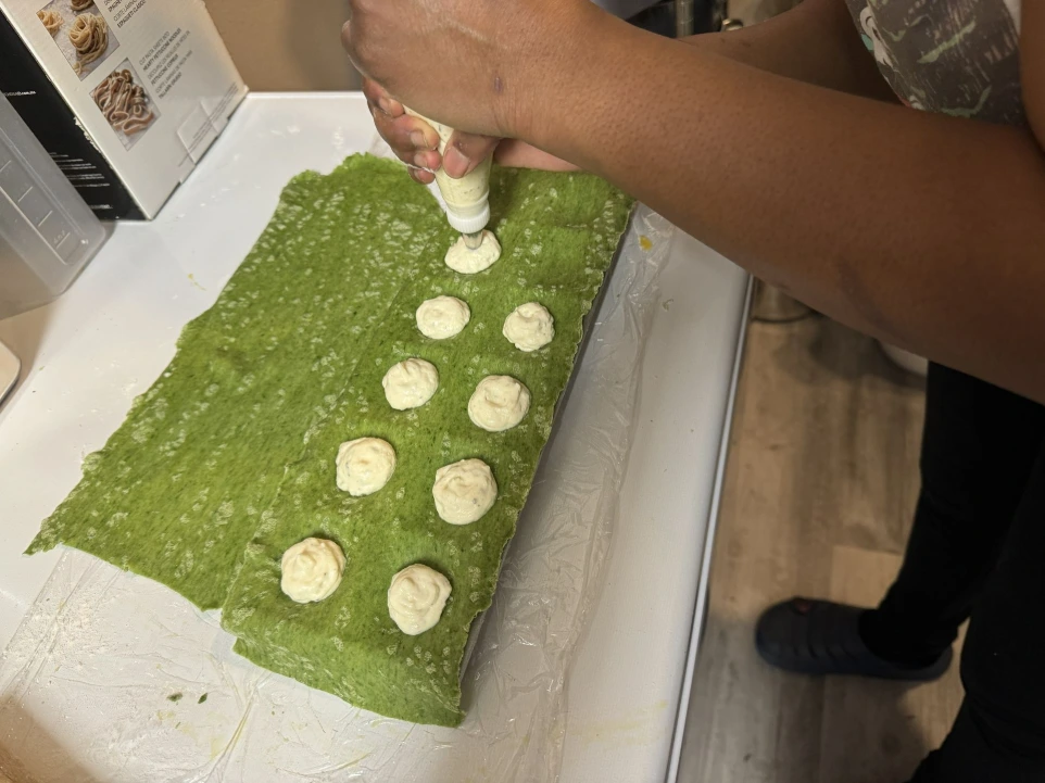 Handmade spinach ravioli being filled with ricotta cheese. 